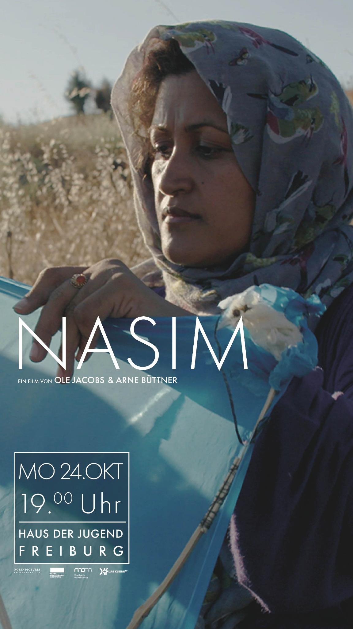 Nasim steht mit einem Flugdrachen in der Hand vor einem Feld